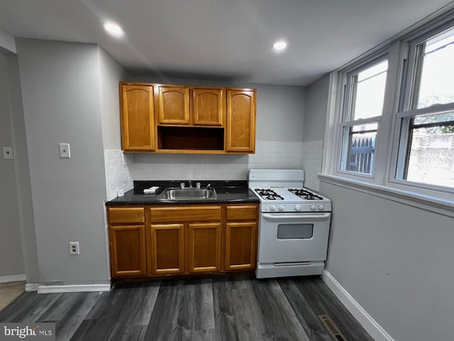 kitchen featuring white gas range, sink, dark hardwood / wood-style floors, and tasteful backsplash