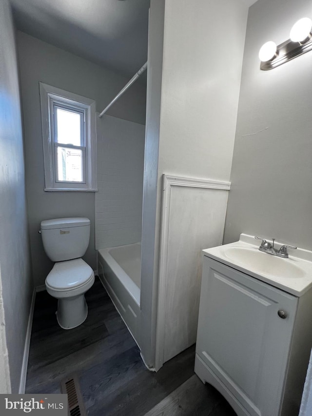 bathroom with visible vents, toilet, wood finished floors, bathing tub / shower combination, and vanity