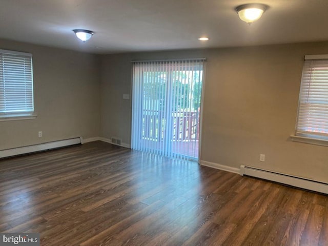 unfurnished room featuring baseboard heating and dark wood-type flooring