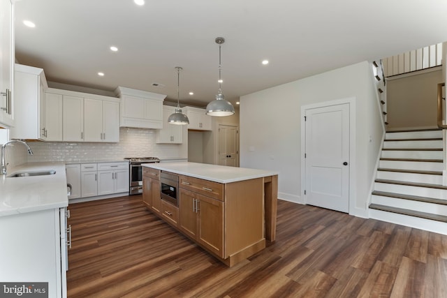 kitchen with a kitchen island, sink, white cabinetry, built in microwave, and stainless steel range oven