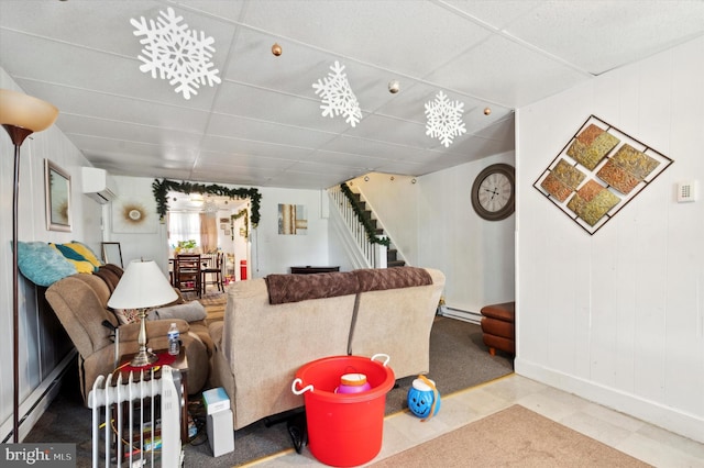 tiled living room featuring an inviting chandelier, a wall unit AC, baseboard heating, and a drop ceiling