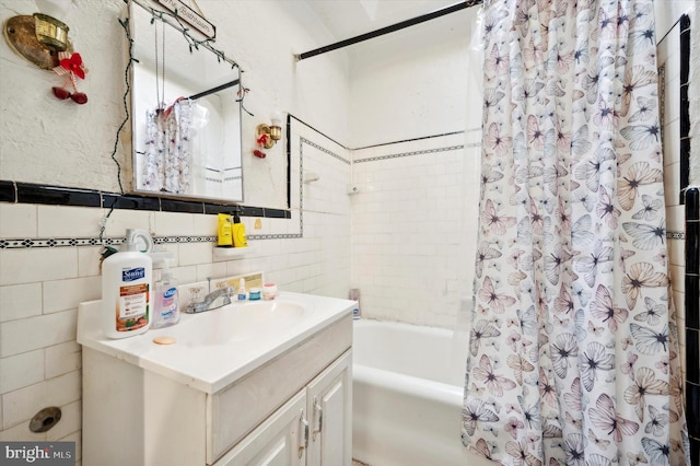 bathroom with vanity, shower / bath combo with shower curtain, and tile walls