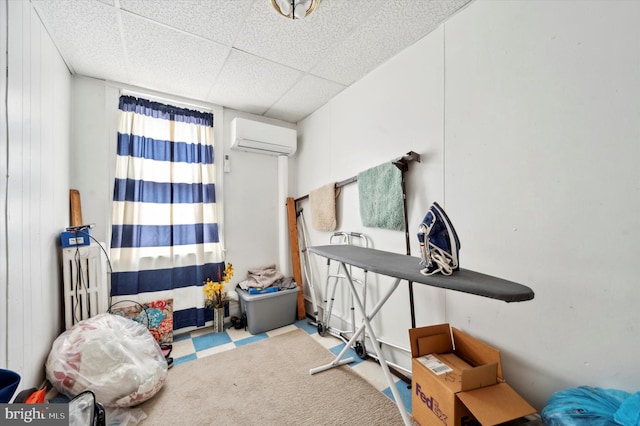 interior space with a wall unit AC, a drop ceiling, and carpet flooring