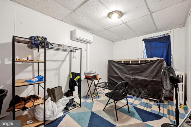 bedroom with a drop ceiling, a wall mounted air conditioner, and radiator heating unit