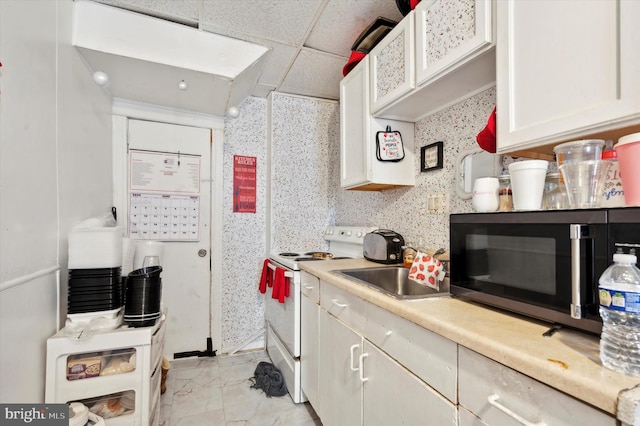 kitchen with white electric stove, white cabinets, sink, a drop ceiling, and light tile patterned flooring