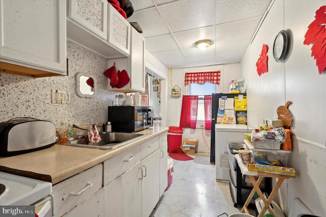 kitchen featuring sink, range, light tile patterned floors, and a paneled ceiling