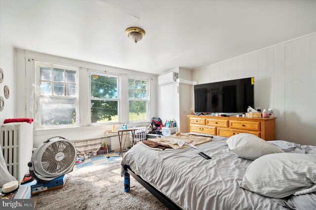 bedroom featuring a wall mounted air conditioner and radiator heating unit