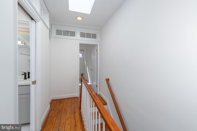 corridor featuring a skylight, sink, and light hardwood / wood-style flooring