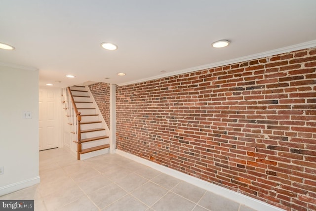 basement with brick wall, ornamental molding, and light tile patterned flooring