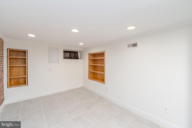 tiled empty room with built in features and crown molding