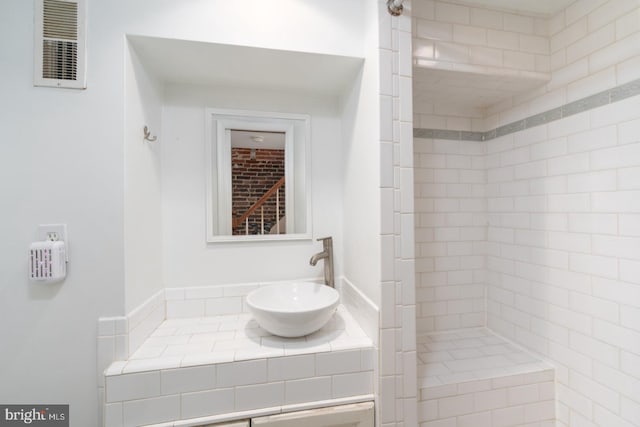 bathroom featuring a tile shower and sink