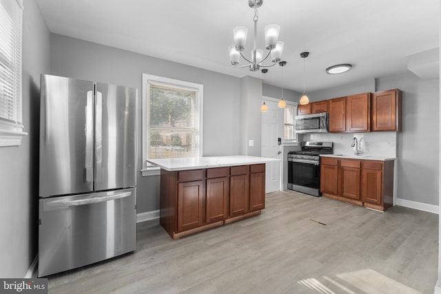 kitchen with appliances with stainless steel finishes, light hardwood / wood-style flooring, decorative light fixtures, and a healthy amount of sunlight