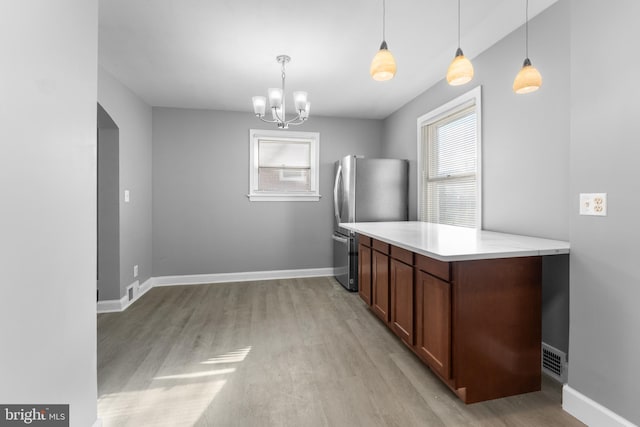 kitchen featuring an inviting chandelier, stainless steel refrigerator, light wood-type flooring, and pendant lighting