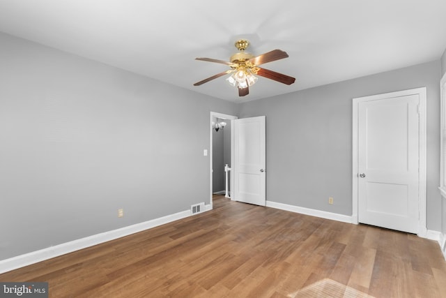 unfurnished bedroom featuring baseboards, a ceiling fan, visible vents, and light wood-type flooring