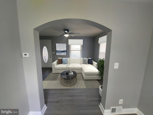 living area featuring a ceiling fan, wood finished floors, arched walkways, baseboards, and visible vents