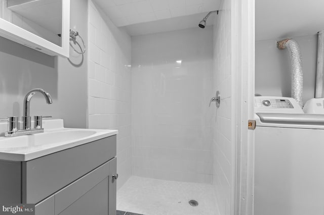 bathroom with vanity, washer / clothes dryer, and a tile shower