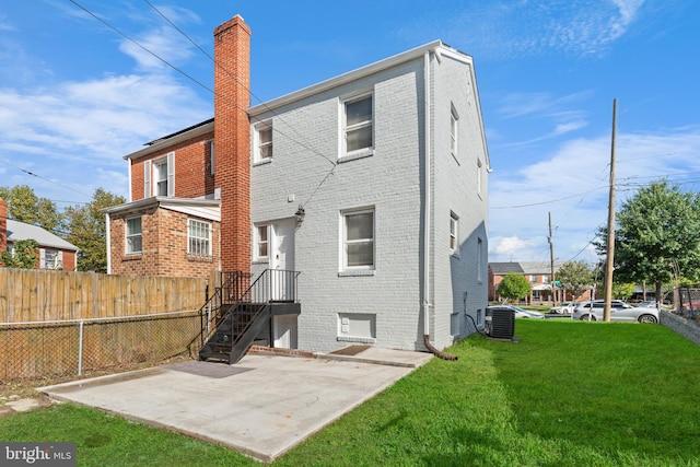 back of property with central air condition unit and a yard