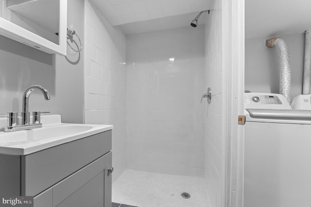 full bath featuring vanity, washer / clothes dryer, and tiled shower
