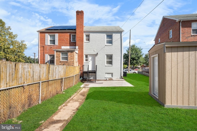 rear view of house with an outdoor structure, a yard, a patio area, and solar panels