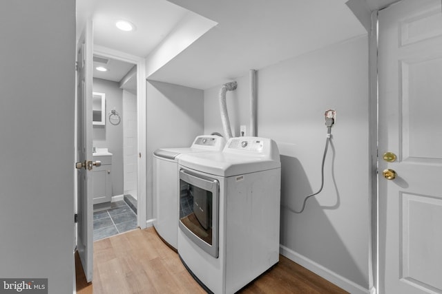 clothes washing area featuring washer and clothes dryer, light wood-type flooring, baseboards, laundry area, and recessed lighting