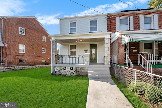 view of front facade with brick siding, a porch, fence, and a front yard