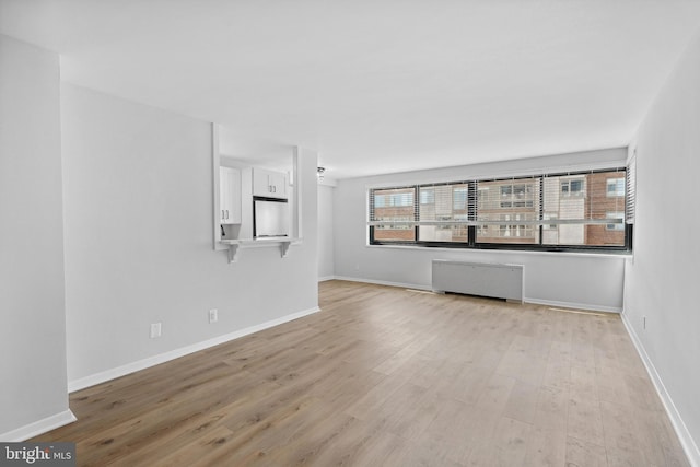 unfurnished living room featuring radiator and light wood-type flooring