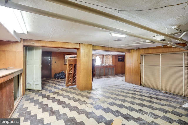 basement featuring a textured ceiling and wood walls