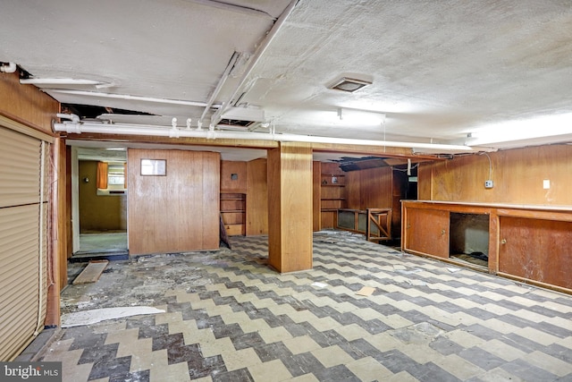 basement with a textured ceiling and wood walls