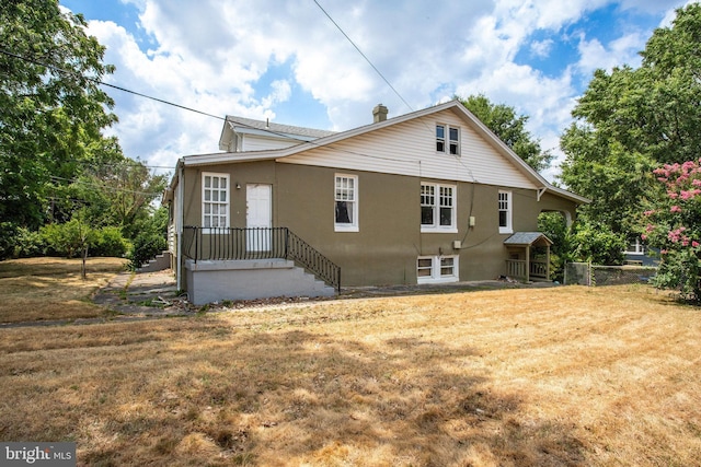 rear view of property featuring a lawn