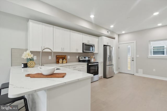 kitchen with appliances with stainless steel finishes, kitchen peninsula, sink, and white cabinets