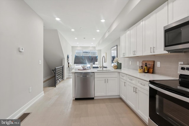 kitchen featuring sink, white cabinetry, tasteful backsplash, kitchen peninsula, and stainless steel appliances