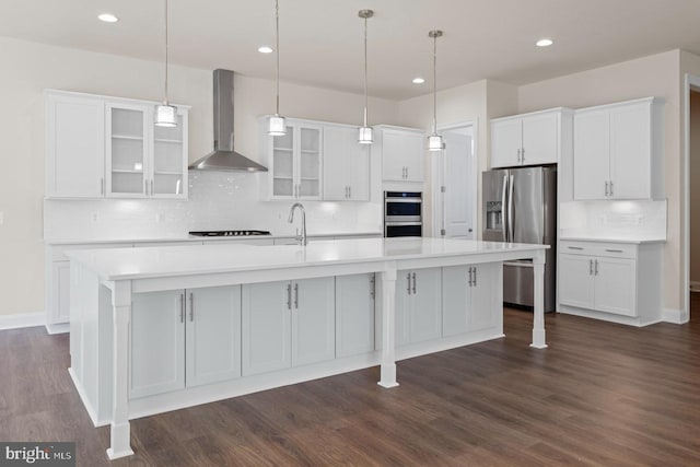 kitchen featuring decorative backsplash, appliances with stainless steel finishes, dark hardwood / wood-style flooring, and wall chimney exhaust hood