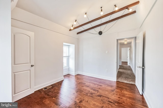 spare room with beam ceiling and dark hardwood / wood-style flooring