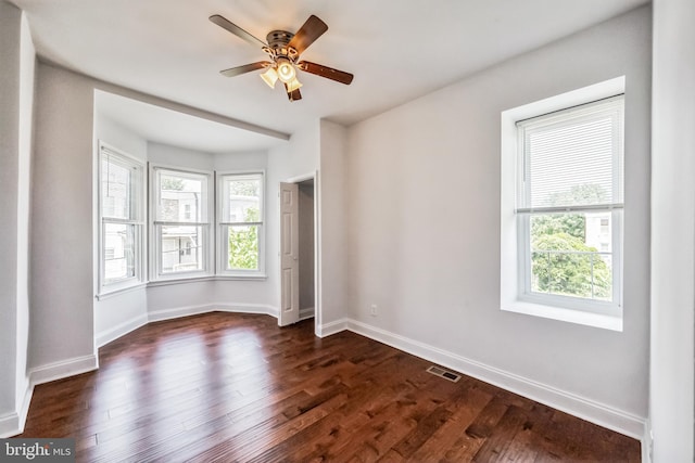 empty room featuring plenty of natural light, dark hardwood / wood-style floors, and ceiling fan