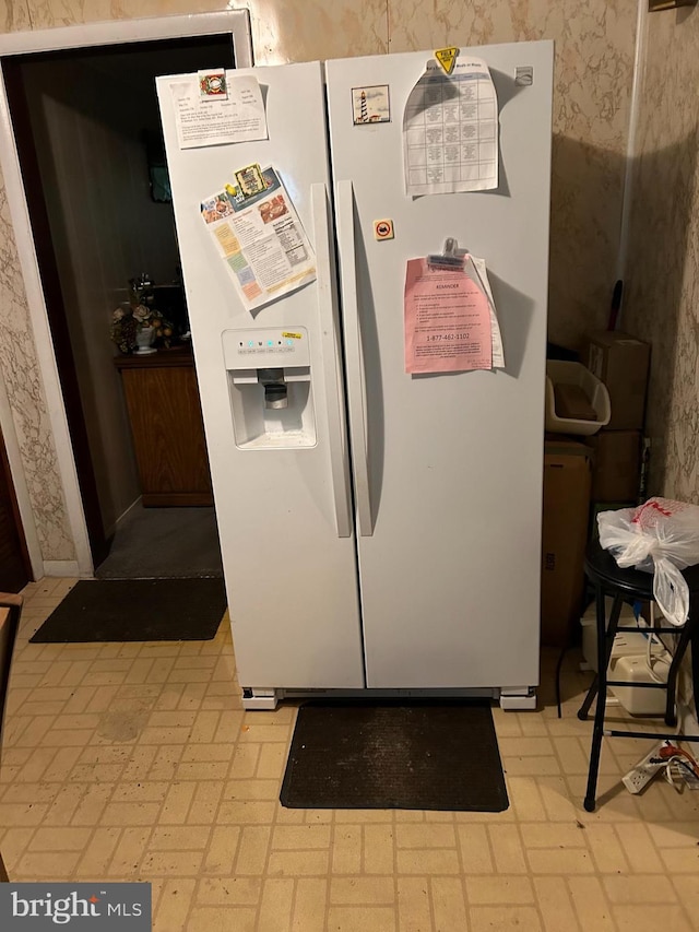 interior space featuring white fridge with ice dispenser, brick floor, and wallpapered walls