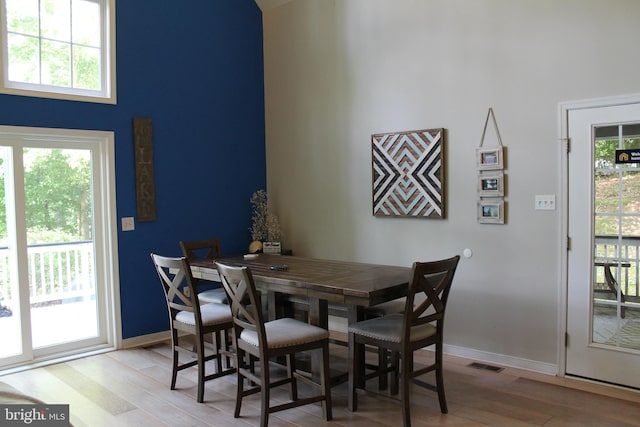 dining room with light hardwood / wood-style floors and a high ceiling