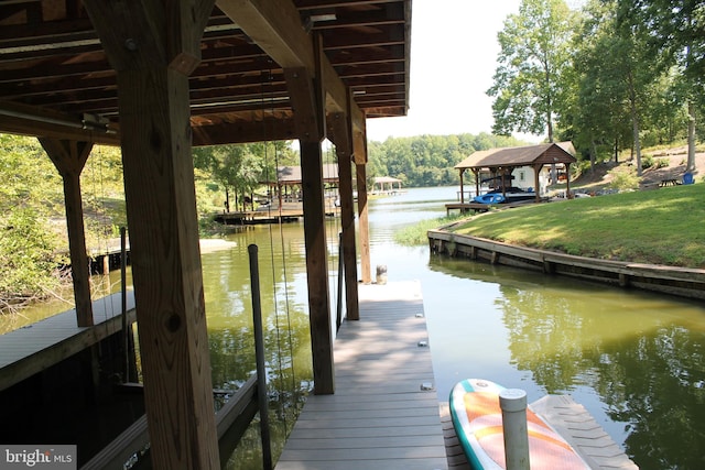 dock area with a gazebo, a water view, and a lawn