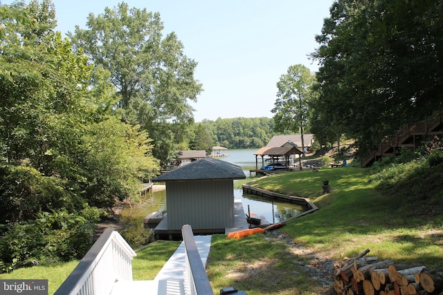 view of side of home featuring a water view, a boat dock, and a lawn