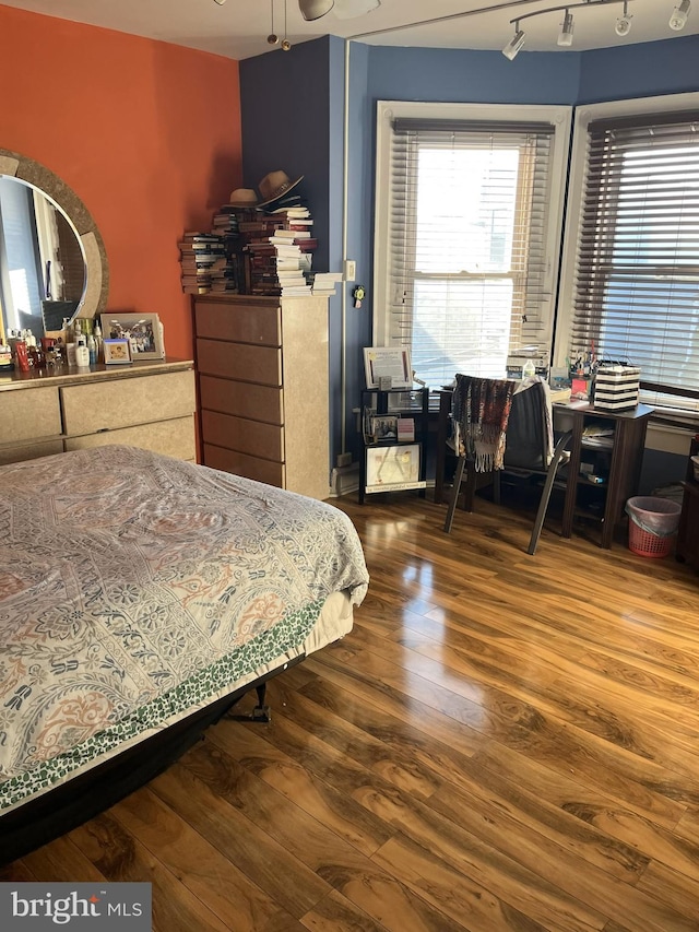 bedroom featuring hardwood / wood-style flooring and rail lighting