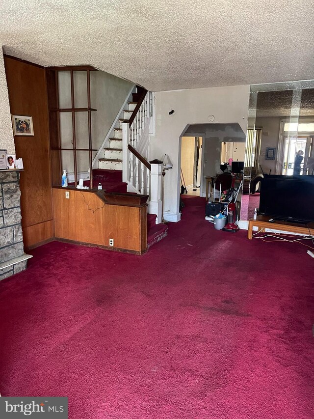 living room featuring a fireplace, carpet, and a textured ceiling