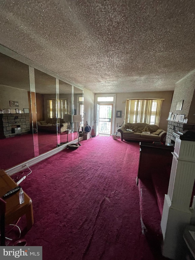 unfurnished living room featuring a textured ceiling, carpet flooring, and a stone fireplace