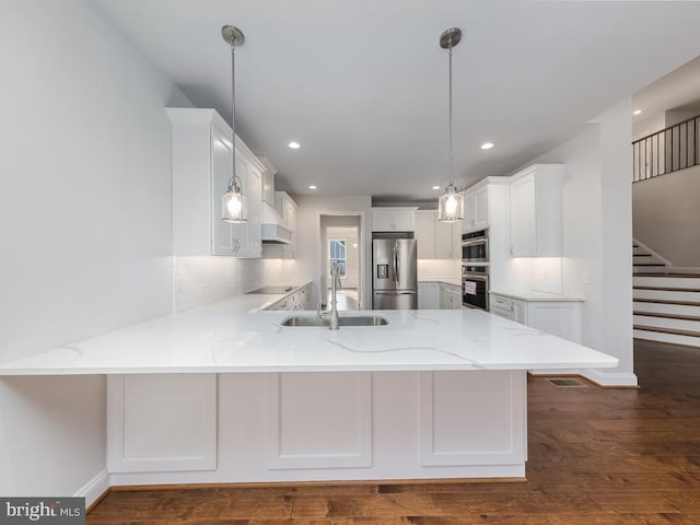 kitchen featuring kitchen peninsula, appliances with stainless steel finishes, white cabinetry, and hanging light fixtures