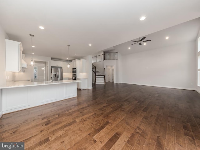 kitchen featuring stainless steel refrigerator with ice dispenser, ceiling fan, dark hardwood / wood-style flooring, pendant lighting, and white cabinets