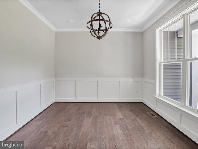 empty room with a notable chandelier, crown molding, and hardwood / wood-style flooring