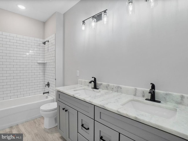 full bathroom featuring tiled shower / bath combo, vanity, and toilet