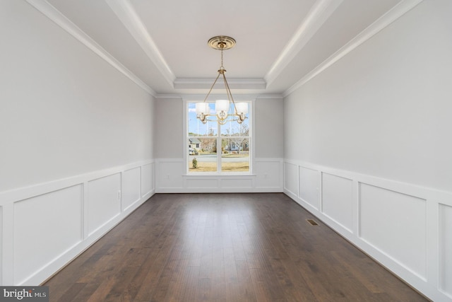 unfurnished dining area featuring crown molding, dark hardwood / wood-style floors, an inviting chandelier, and a tray ceiling