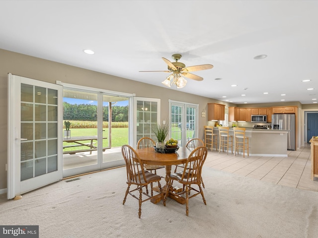 dining space with ceiling fan, light colored carpet, and french doors