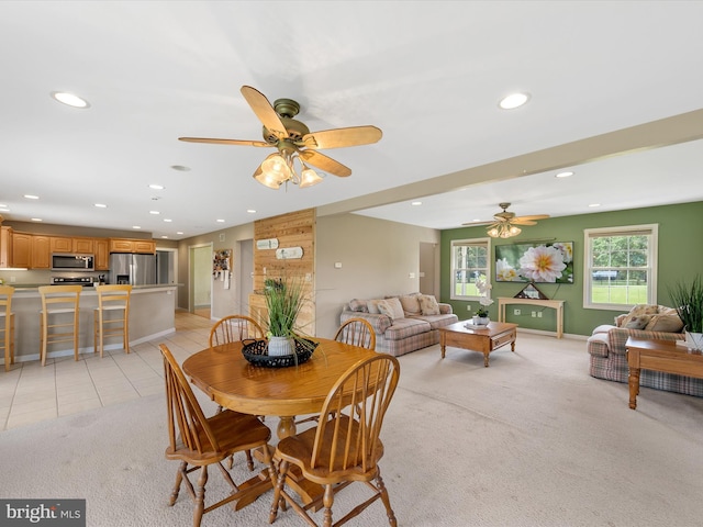 dining space with ceiling fan and light carpet