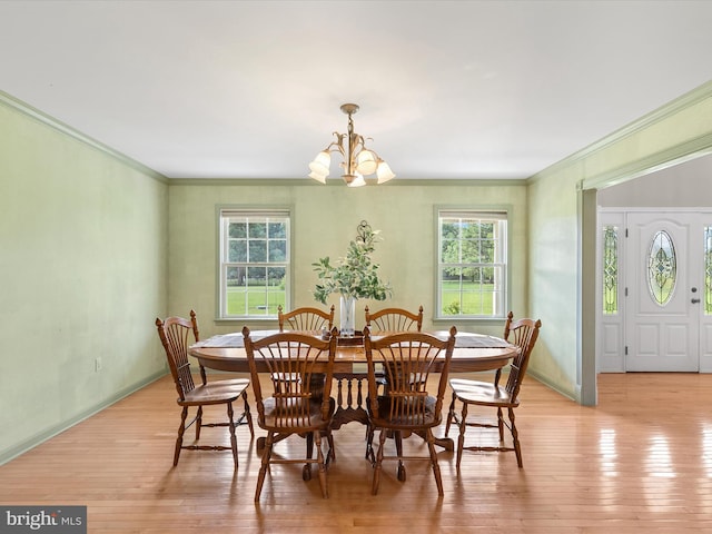 dining room with light wood-type flooring, a notable chandelier, and crown molding