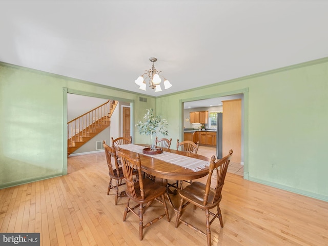 dining room with light wood-type flooring, a notable chandelier, and ornamental molding